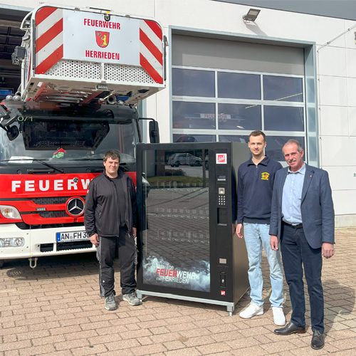 Menschen neben einem Automaten und einem Feuerwehrauto