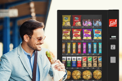 Ein essender Mann vor einem Automaten